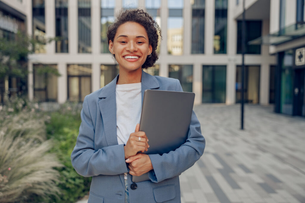 A happy professional hired for a marketing career holding her laptop.